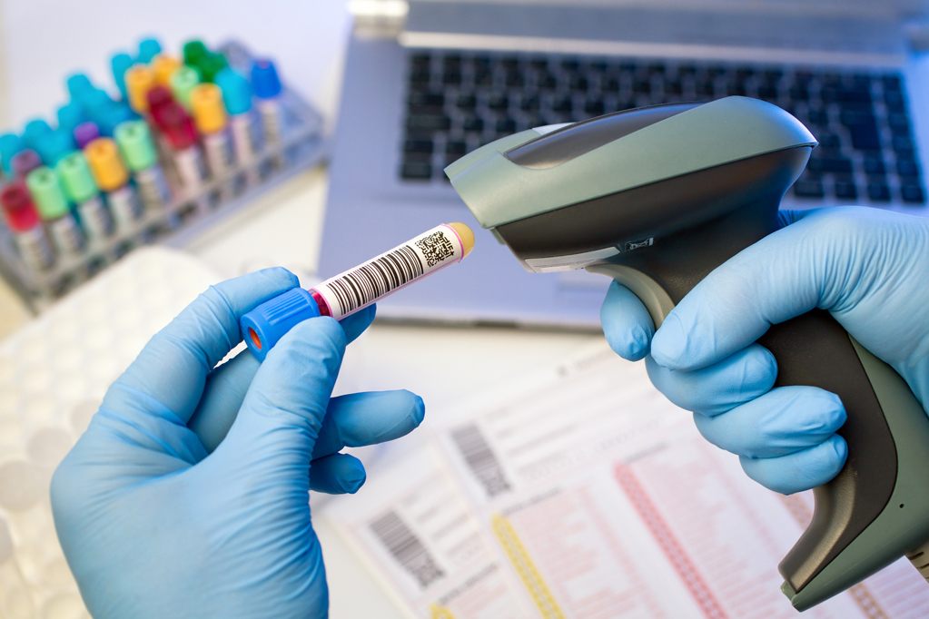 hands scanning barcodes for tracking of blood sample technician hands scanning barcodes on biological sample tube in the lab of blood bank